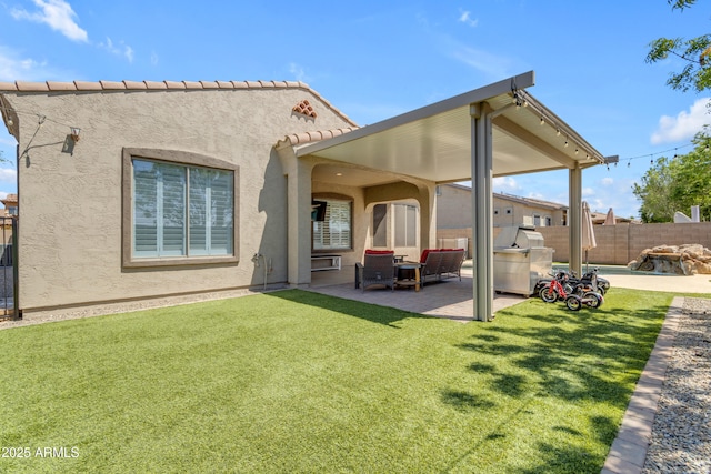 rear view of house featuring a patio area, stucco siding, fence, and a lawn