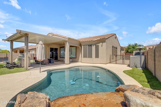 back of house featuring a fenced backyard, stucco siding, a patio, a tile roof, and a fenced in pool