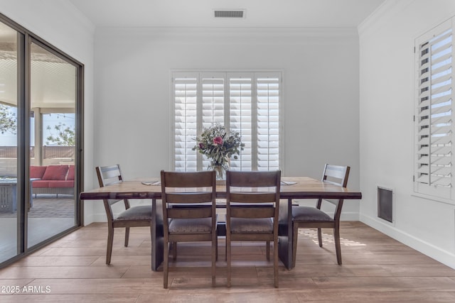 dining space featuring crown molding, wood finished floors, baseboards, and visible vents