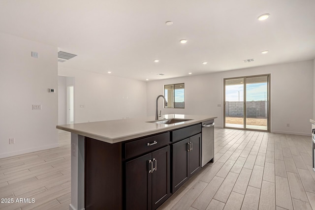 kitchen featuring an island with sink, sink, stainless steel dishwasher, and light hardwood / wood-style flooring