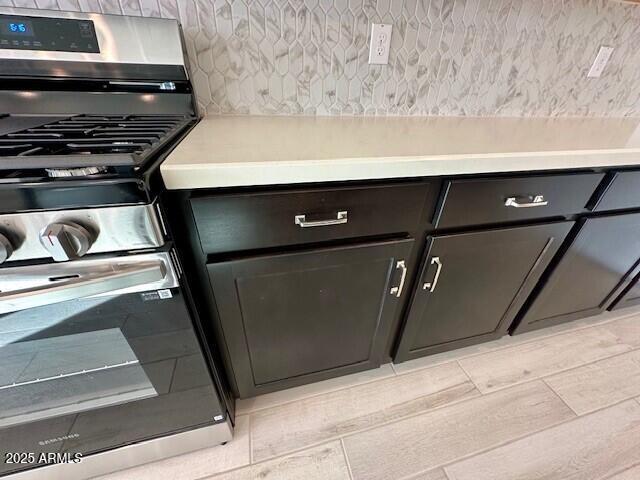 interior details featuring stainless steel range with gas stovetop and decorative backsplash