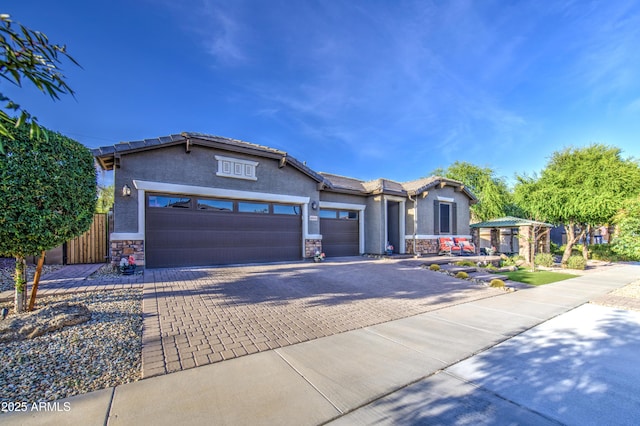 view of front of house with stucco siding, an attached garage, decorative driveway, and stone siding