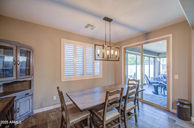 dining room with wood tiled floor, baseboards, a chandelier, and visible vents