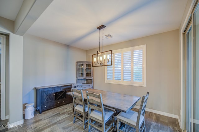 dining area featuring a chandelier, baseboards, visible vents, and wood finished floors