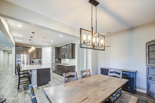 dining space with recessed lighting, light wood finished floors, baseboards, and an inviting chandelier
