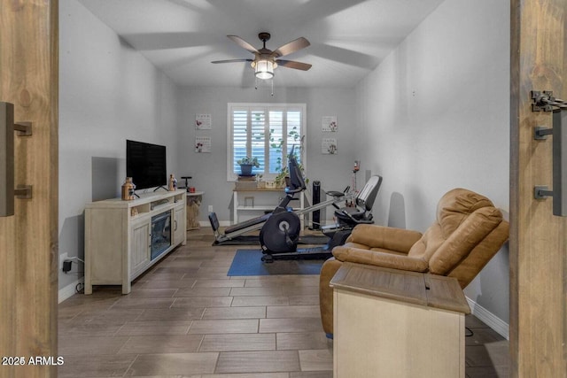 workout room with baseboards, ceiling fan, and wood finish floors