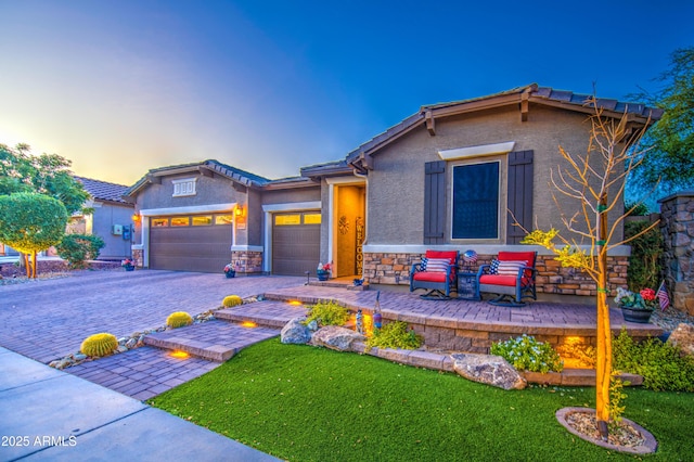 craftsman-style house featuring a lawn, a garage, decorative driveway, stone siding, and stucco siding