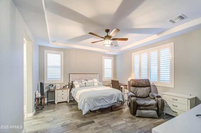 bedroom with visible vents, multiple windows, and a raised ceiling