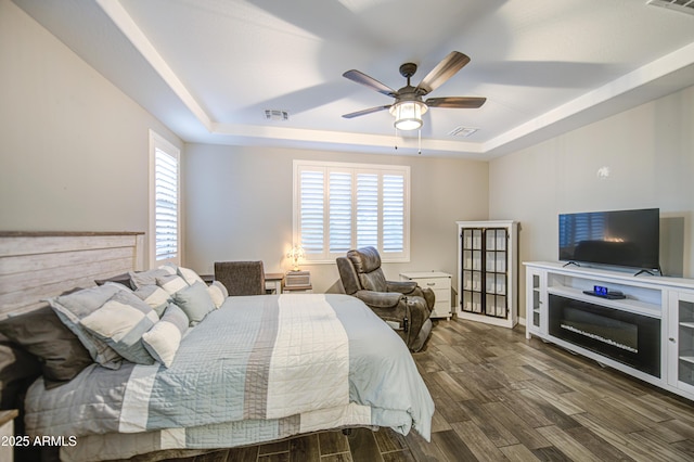 bedroom featuring visible vents, a raised ceiling, and wood finished floors