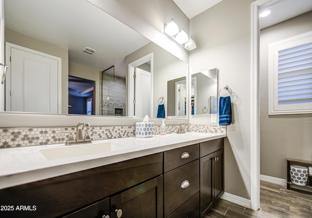 bathroom featuring double vanity, tasteful backsplash, a sink, and wood finished floors