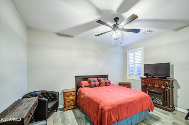 bedroom featuring visible vents, a ceiling fan, baseboards, and wood finished floors