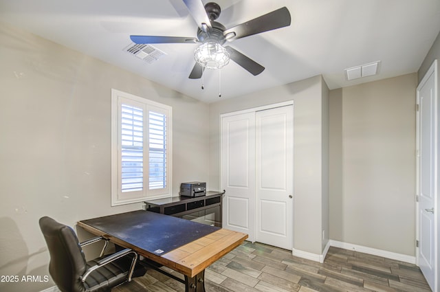 office space featuring visible vents, a ceiling fan, baseboards, and wood finished floors