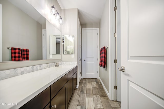 bathroom with baseboards, wood finished floors, and vanity