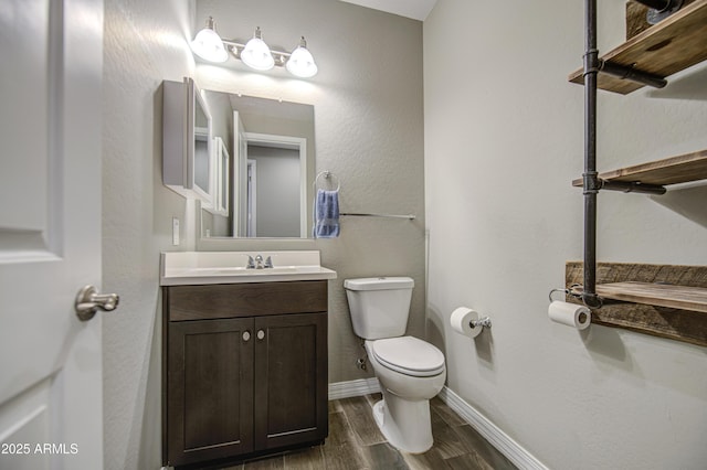 bathroom with toilet, baseboards, wood finished floors, and vanity