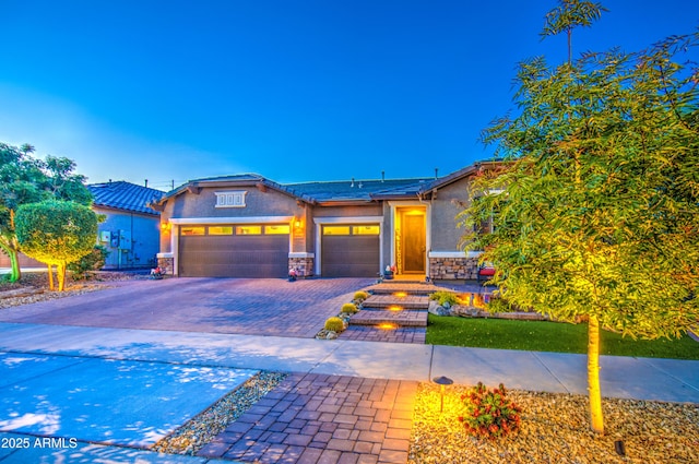 view of front of house with a garage, stone siding, stucco siding, a tiled roof, and driveway