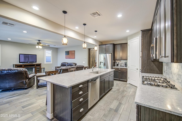 kitchen featuring visible vents, open floor plan, dark brown cabinetry, and stainless steel appliances