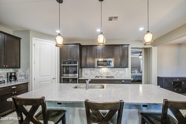 kitchen with visible vents, decorative backsplash, dark brown cabinetry, a sink, and appliances with stainless steel finishes