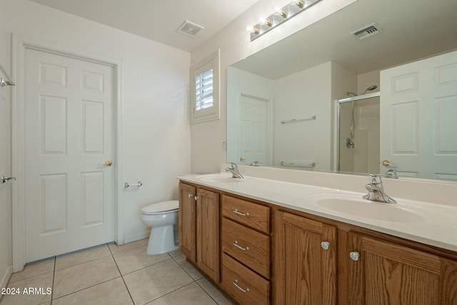 bathroom featuring tile patterned flooring, vanity, toilet, and a shower with door