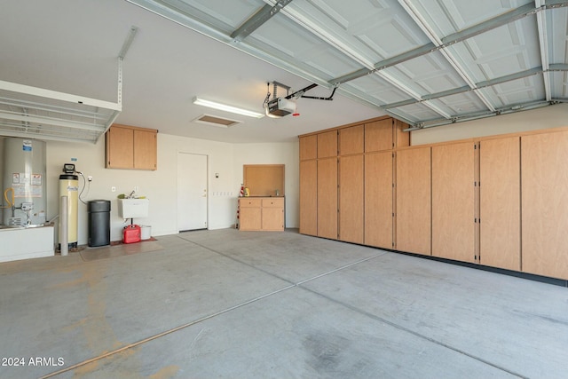 garage with sink, a garage door opener, and water heater