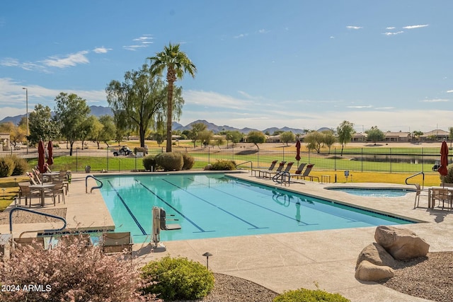 view of pool featuring a mountain view, a community hot tub, a patio area, and a lawn