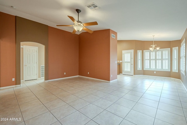 tiled empty room featuring ceiling fan with notable chandelier and vaulted ceiling