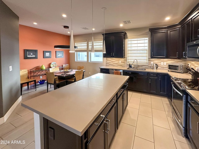 kitchen with visible vents, stainless steel appliances, light countertops, backsplash, and a center island