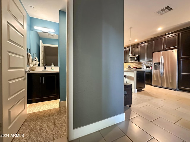 kitchen with visible vents, light countertops, dark brown cabinets, appliances with stainless steel finishes, and tasteful backsplash