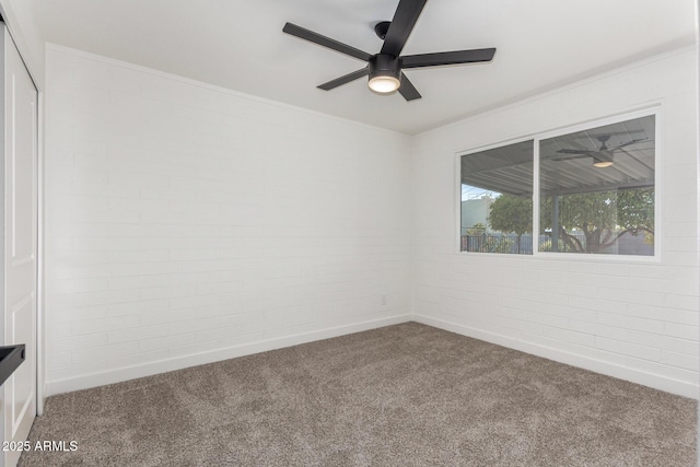 unfurnished room with carpet flooring, brick wall, and ceiling fan