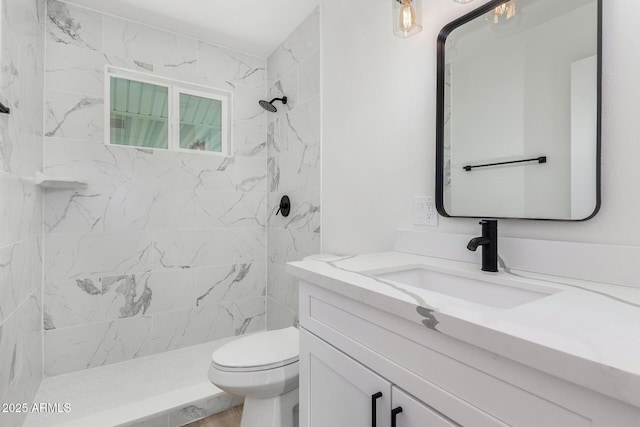 bathroom featuring vanity, toilet, and a tile shower