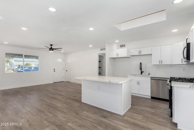 kitchen featuring a kitchen island, hardwood / wood-style floors, white cabinetry, and stainless steel appliances