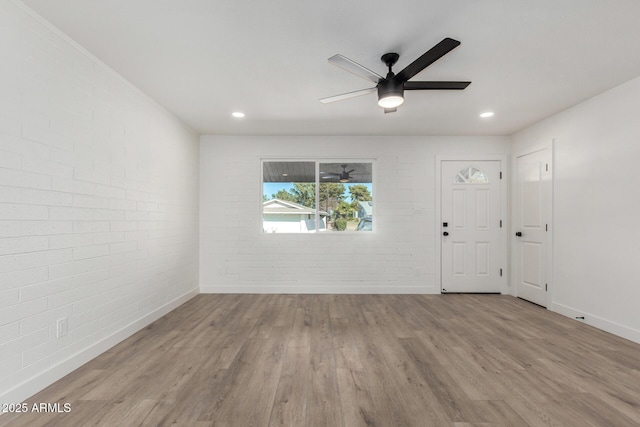 empty room featuring light hardwood / wood-style floors, brick wall, and ceiling fan