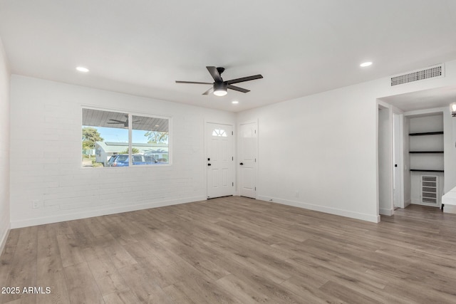 empty room featuring light hardwood / wood-style floors, brick wall, and ceiling fan