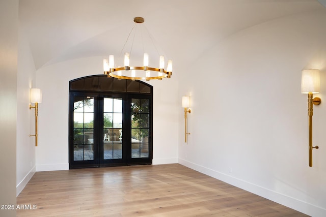 foyer entrance featuring an inviting chandelier, wood finished floors, baseboards, and vaulted ceiling