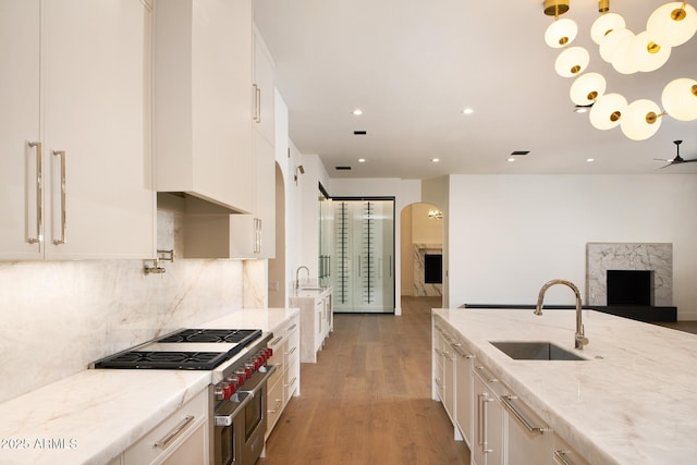 kitchen featuring double oven range, light wood-style flooring, a sink, white cabinetry, and open floor plan