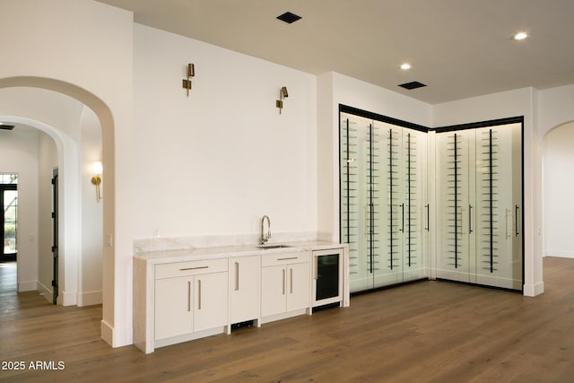 interior space with beverage cooler, dark wood-style floors, and arched walkways