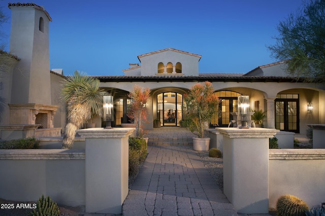 view of front facade with stucco siding, french doors, and a tile roof