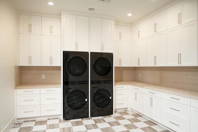 laundry area with recessed lighting, stacked washer / drying machine, cabinet space, and visible vents