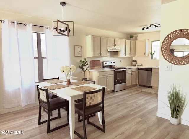 kitchen featuring appliances with stainless steel finishes, light countertops, a notable chandelier, light wood-style floors, and under cabinet range hood