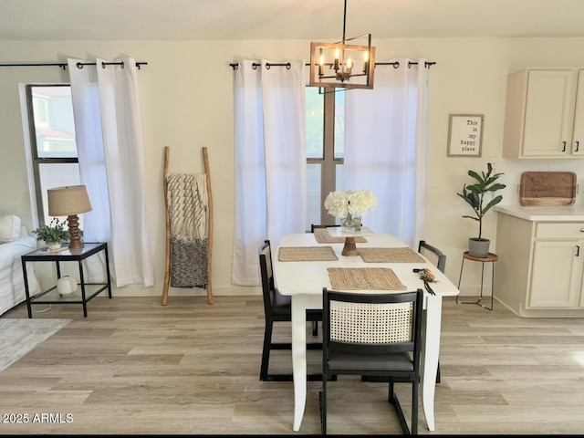 dining area featuring baseboards, a notable chandelier, a healthy amount of sunlight, and light wood finished floors