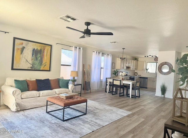 living area featuring visible vents, light wood finished floors, ceiling fan, and baseboards