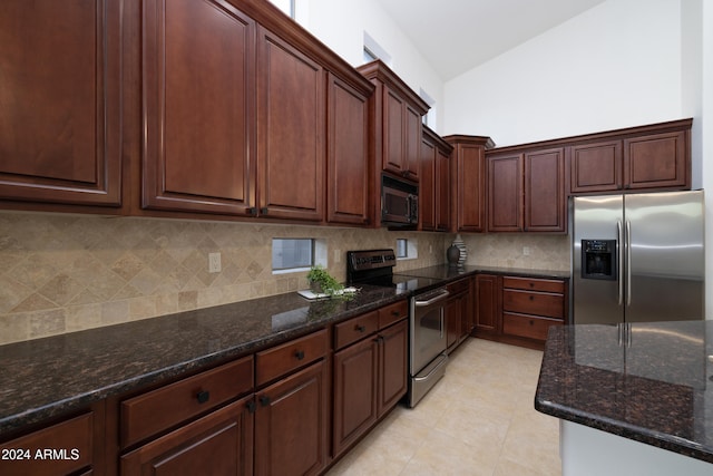 kitchen featuring backsplash, stainless steel appliances, vaulted ceiling, and dark stone counters