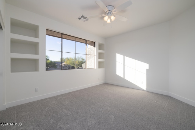 carpeted empty room with built in features and ceiling fan