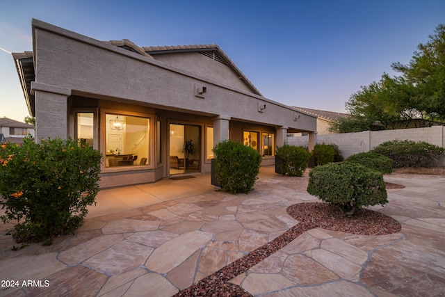 back house at dusk featuring a patio area