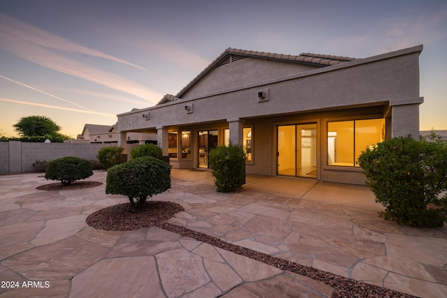 back house at dusk featuring a patio