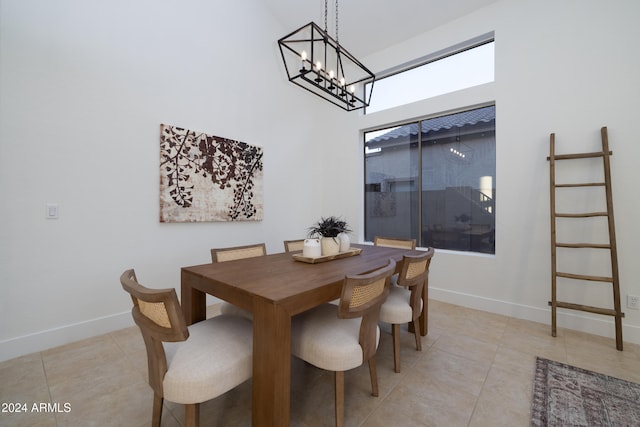 tiled dining area featuring a notable chandelier and a high ceiling