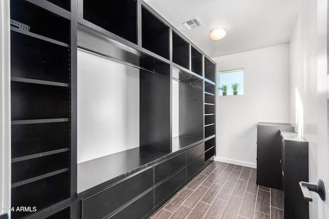 walk in closet with dark wood-type flooring