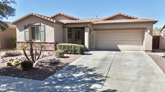 single story home featuring a garage, a tile roof, concrete driveway, and stucco siding