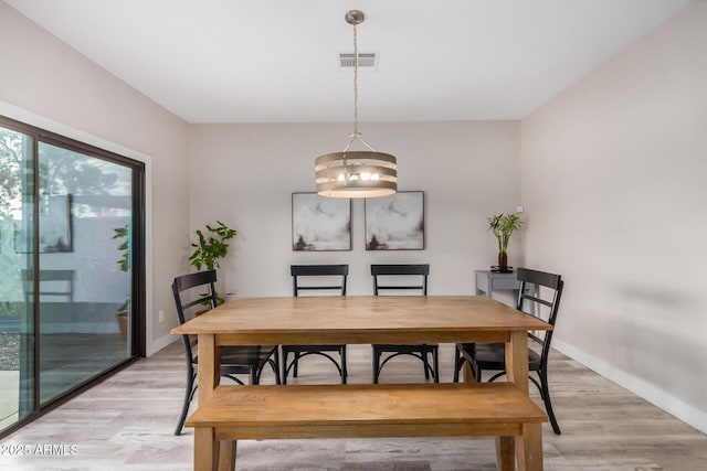 dining room with light wood-type flooring, visible vents, and baseboards