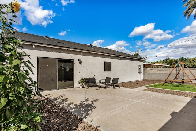 back of property featuring a patio, a playground, fence, and stucco siding