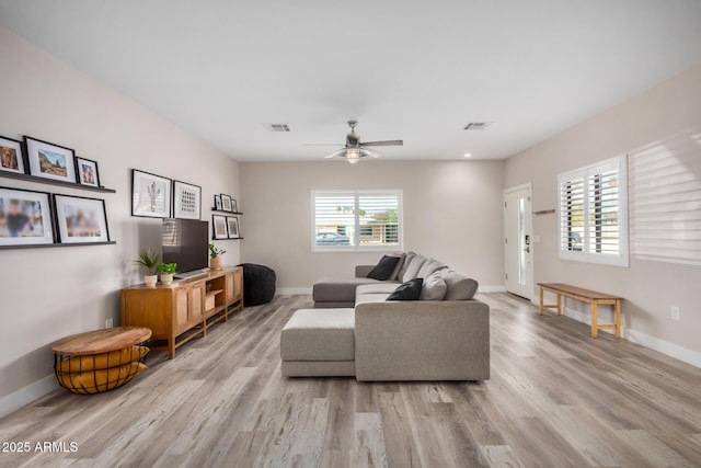 living room featuring light wood-style flooring, visible vents, and baseboards